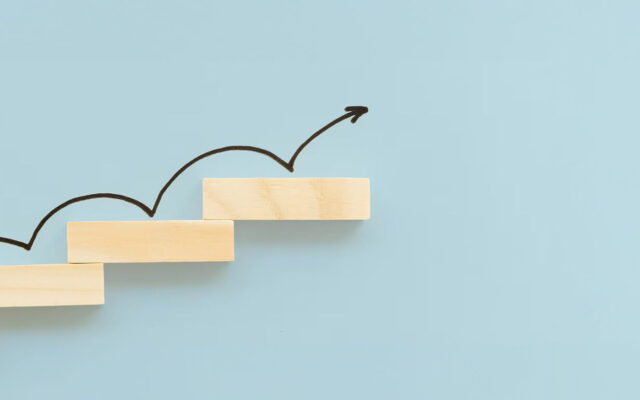 Holzstufen mit aufsteigendem Pfeil vor hellblauem Hintergrund