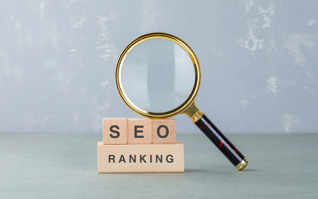 Holzbausteine mit den Buchstaben "SEO" und "Ranking" daneben eine Lupe