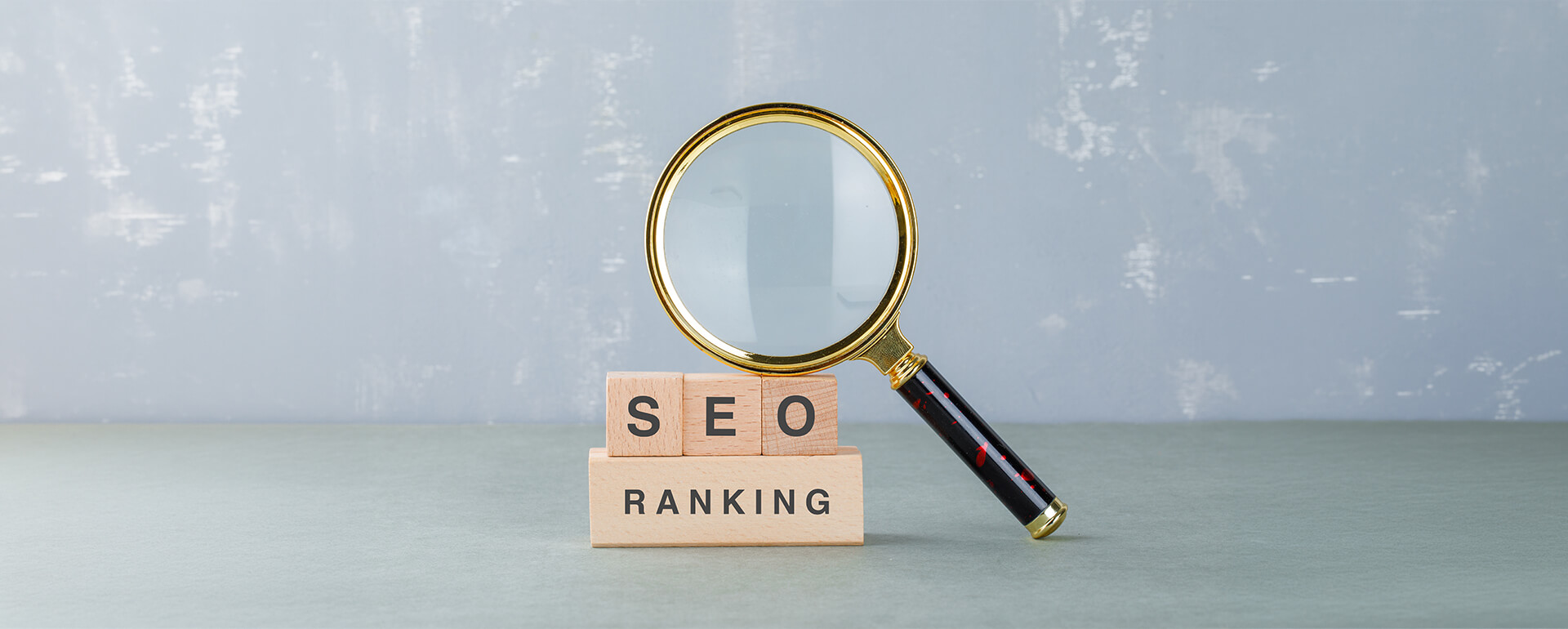 Holzbausteine mit den Buchstaben "SEO" und "Ranking" daneben eine Lupe